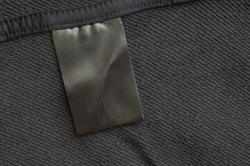 Blank black laundry care clothes label on black fabric texture background