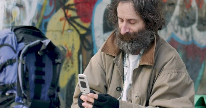 Man with a backpack and beard making a phone call on a mobile phone outside