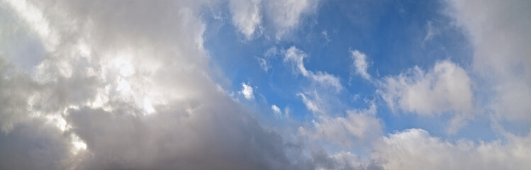 Fototapeta premium Blue sky with clouds in sunlight, wide cloudscape background panorama