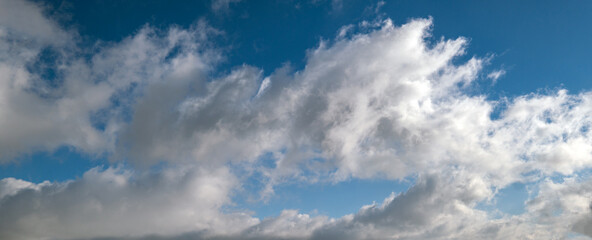 Blue sky with clouds in sunlight, wide cloudscape background panorama