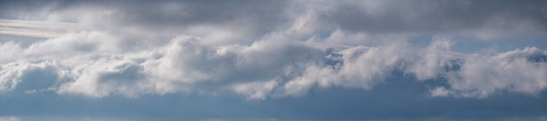 Blue sky with clouds in sunlight, wide cloudscape background panorama