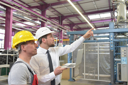businessman and worker meeting in a factory - maintenance and repair of the industrial plant