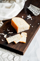 Delicious Dutch gouda cheese with cheese blocks on an old wooden white table. Piece of cheese on a dark board