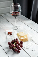 Beautiful still life with a hard piece of cheese and red wine in a glass on a white wooden background