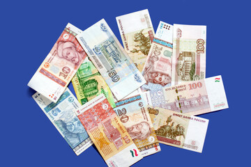 Obraz na płótnie Canvas Photo of somoni bank notes from Tajikistan and Russian ruble bank notes on blue background. 