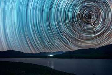Beautiful starry sky with star trails behind the trees silhouette.  Space background. Abstract long...