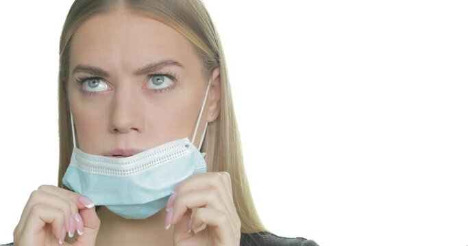 A woman struggles to breathe in her PPE mask and pulls it down to take a breath.