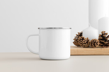 Enamel white mug mockup with candles on a table. Christmas decoration