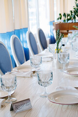 blurred background  elegant table setting with white plate and crystal glass and sign reserved