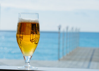 fresh cold glass of beer on a sea restaurant terrace in a sunny day, copy space blurred background