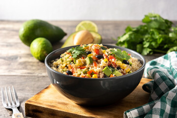 Mexican salad with quinoa in bowl on wooden table