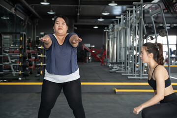 plump chubby Asian woman with personal trainer help gain muscle and lose fat in gym with fitness exercise