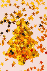 Golden sparkles stars and Christmas tree on a pink background, festive flatlay. Selective focus