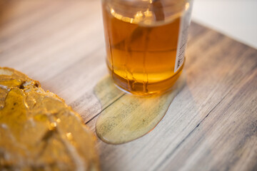 Honey jar and a slice of bread with peanut butter on wooden table