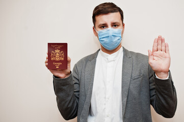 European man in formal wear and face mask, show Georgia  passport with stop sign hand. Coronavirus lockdown in Europe country concept.