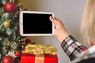 Senior woman holds Digital tablet mock up template for Christmas app presentation or website promotion.