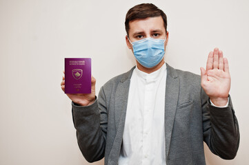 European man in formal wear and face mask, show Kosovo passport with stop sign hand. Coronavirus...