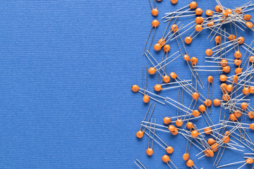 Radio components. Disc ceramic capacitor of orange color on a blue background with copy space close-up. Capacitor specifications: 18pF 50v.