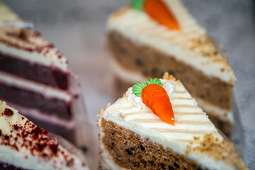 Carrot and red velvet cake slices pieces sweet dessert with cream cheese frosting on retail display at cafe or restaurant in Chelsea neighborhood of London, United Kingdom