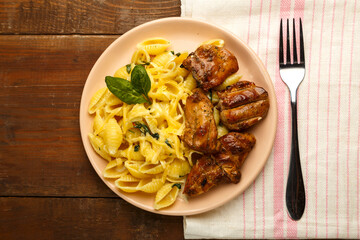 Cheese plate of pasta in a creamy sauce with cheese and chicken on the table on a napkin next to a fork.