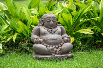 Meditating Buddha statue in tropical garden in Bali, Indonesia