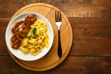 A plate of pasta in a creamy sauce with cheese and chicken on a round stand next to a fork. copy space.