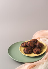 Traditional Russian vanilla marshmallows in chocolate glaze in green and yellow plates on gray background. Vertical. Copy space