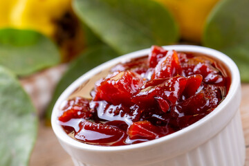 Homemade quince jam in a glass jar on an old wooden background. Fresh quince fruits and leaves and quince jam.