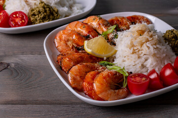 selected focus a plate of fried shrimp and white rice with pesto sauce on a brown wooden table