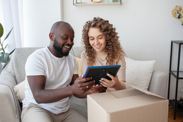 Beautiful and stylish couple of future parents closely looking at the printed photo in frame and smile while sitting in living room on sofa. People, happiness and resting concept.