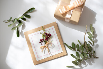 Beautiful layout with flowers decoration and card mock up on white desk background, top view, flat lay. Wedding invitation or Mother Day greeting concept