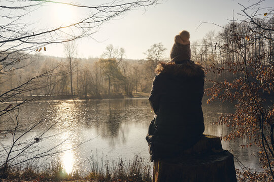 A Women is sitting alone on a tree stump and gaze into the distance