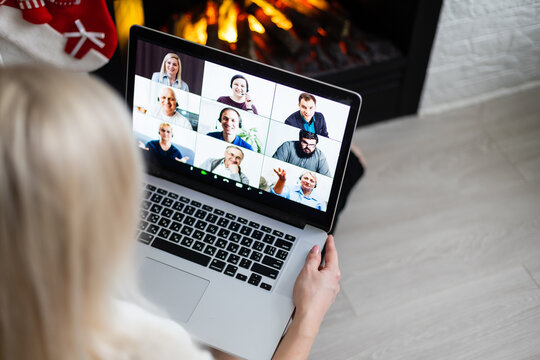 Cheerful woman making video call on Christmas day and greeting somebody, looks happy, clenching fist like winner, looks at screen of device, posing indoor near fireplace