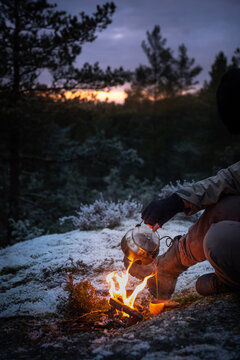 Coffee brewed on a woodfire in the forests poured into a wooden cup at sunset.