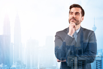 Fototapeta premium Young handsome businessman in suit with hand on chin thinking how to succeed, new career opportunities, MBA. Kuala Lumpur on background. Double exposure.