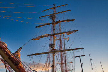 Big historic sailing ship in the port. Yachts and boats at sea against the backdrop of the setting...