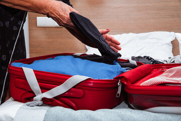 Packing clothes into a suitcase. Concept of packing for a trip, moving out.