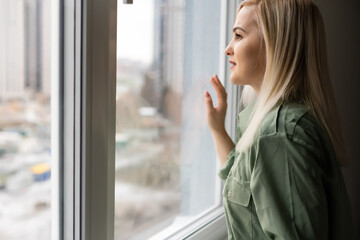 Fototapeta premium Sad beautiful woman looking through a window