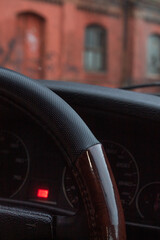 Part of the steering wheel in the case against the background of a brick building