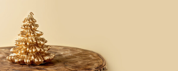 Beautiful golden candle in the form of a Christmas fir tree on natural wooden stand as cross...