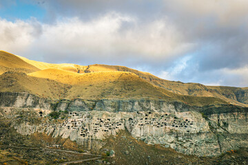 Aerial perspectve of Vardzia-cave city from above with paravani river and autumn nature in foreground. Historical unesco sites Georgia.