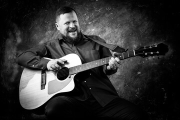 Mature musician plays acoustic guitar emotional studio portrait.