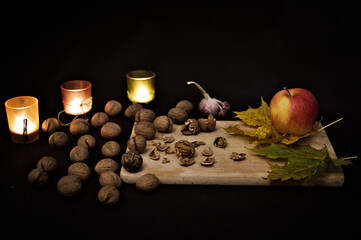 Klimatyczne jesienne orzechy, jabłko, deska, łupiny, świece, liście.