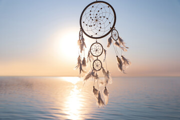 Beautiful handmade dream catcher near river at sunset. Space for text
