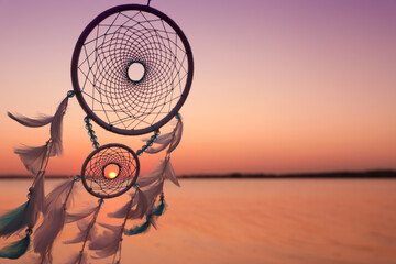 Beautiful handmade dream catcher near river at sunset. Space for text - Powered by Adobe