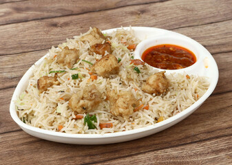 Indian cuisine Healthy and tasty chicken fried rice with tomato sauce served in white bowl over a rustic wooden background, selective focus
