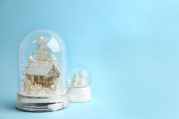 Beautiful snow globes on light blue background, space for text