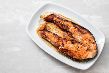 fried salmon on white dish on ceramic background
