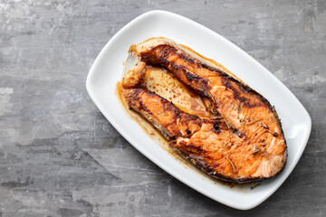fried salmon on white dish on ceramic background