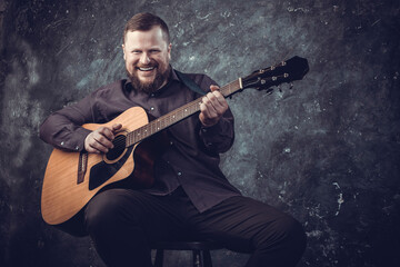 Obraz na płótnie Canvas Mature musician plays acoustic guitar emotional studio portrait.